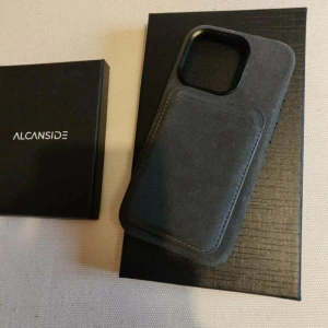 IPhone 15 pro skal + korthållare  - Säljer mitt skal plus korthållare från Alcanside Skalet har inbyggt MagSafe magnet är gjort av Alcantara som använd som tyg i blandannat Porsche,bmw och Ferraris bilar (både skal och plånboken är av samma material) Använt fåtal gånger är som ny. 