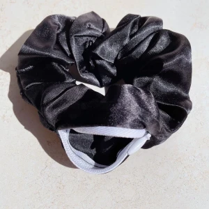 scrunchie - Snygg och glansig svart scrunchie i satin. Perfekt för att ge en elegant touch till din frisyr. den har en dragkedja där du kan lägga små saker