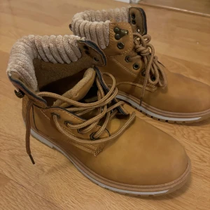 Bruna boots med snörning - Säljer ett par snygga bruna boots i skinn med snörning. Aldrig använda. De har en bekväm och vadderad krage i ribbat material som ger extra komfort. Perfekta för höst och vinter med sin robusta design och slitstarka sula.