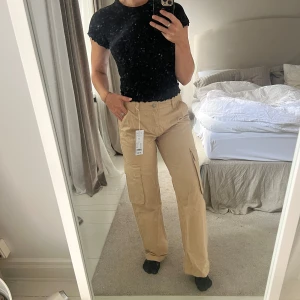 Beige cargobyxor - Säljer ett par snygga beige cargobyxor i storlek 34. De har en avslappnad passform med stora fickor på sidorna, perfekt för en casual look. Byxorna är tillverkade i ett slitstarkt material och har en midwaist design. Perfekta för hösten. Byxorna är helt oanvända, prislappen kvar. 