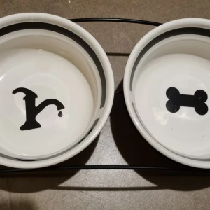 Matbar med mat- och vattenskål  - Sparsamt använd matbar med mat- och vattenskål. Material är i porslin och storlek 2x600ml/15cm i diameter. Mindre skavanker i matskålen som var där när jag köpte den. Kan användas för både hund och katt!