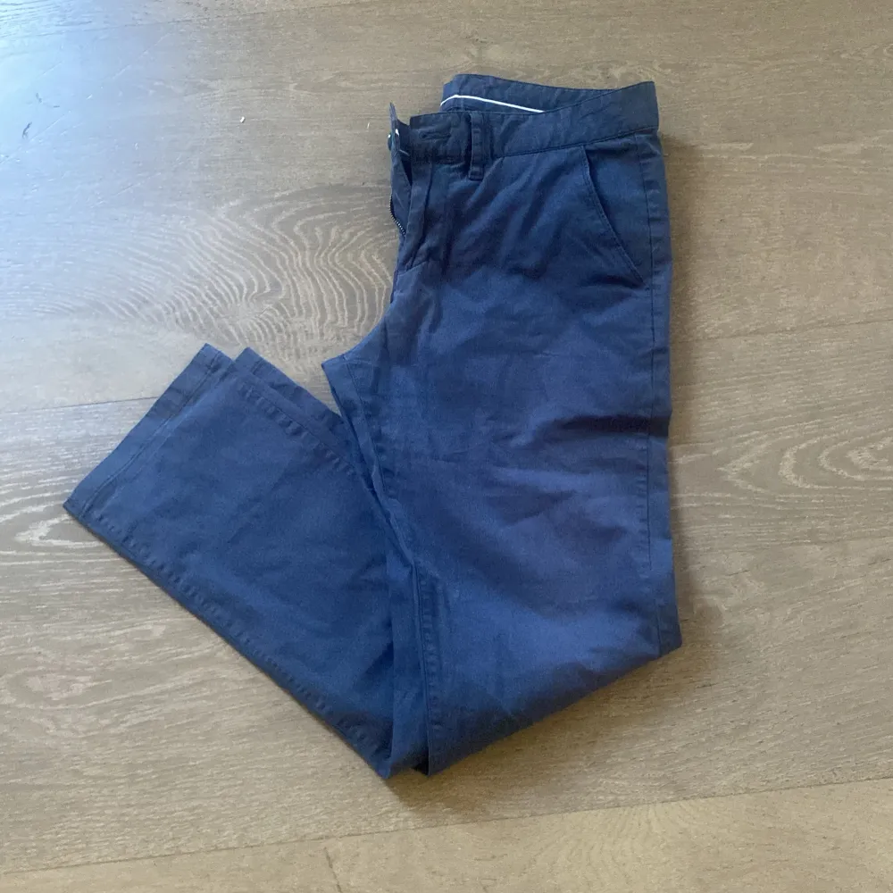 Säljer ett par snygga mörkblå byxor från Peak Performance. De är i storlek 32/34 och har en stilren design med raka ben och en normal passform. Perfekta för både vardag och lite mer uppklädda tillfällen. Byxorna är tillverkade i ett bekvämt material som känns skönt mot huden.. Farkut & Housut.