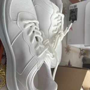 Vita sneakers med snörning - Säljer ett par fräscha vita sneakers i nyskick. De har en stilren design med snörning och en bekväm sula. Perfekta för vardagsbruk och passar till det mesta i garderoben. Storlek dam 37.