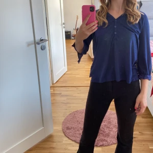 Mörkblå blus med knappar - Säljer en mörkblå blus med knappar framtill. Den har trekvartsärmar och en liten bröstficka. Perfekt för både vardag och lite finare tillfällen. Blusen är i ett mjukt och bekvämt material.