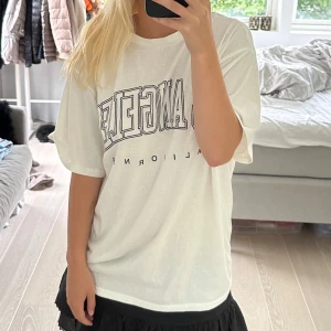 Vit t-shirt med Los Angeles-tryck - Säljer en vit t-shirt med ett coolt Los Angeles-tryck på framsidan. Den är i en skön och avslappnad passform, perfekt för en casual look. T-shirten har korta ärmar och är i bra skick. Storlek S men är oversized