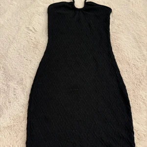 Svart klänning - Säljer denna fina svarta klänning som man knyter vid halsen. Väldigt fint material och använd en gång. 