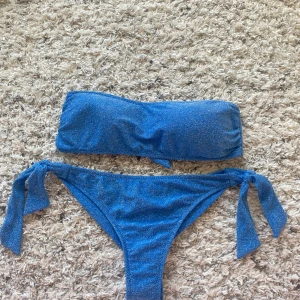 Glitter bikini - Blå glittrig bikini, passar S och Xs.  Ett avtagbart band medföljer till överdelen om man vill ha det också. Både överdelen och underdelen går att justera efter egen preferens.  Köpt förra året i Italien.