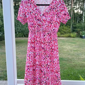 Blommig klänning - En blommig klänning köpt på PMU Second hand som dessvärre aldrig blev använd av mig. Passar mig som är storlek S men skulle säkert även passa till storlek M då resåren i midjan är rätt generös 💕 Vita knappar framtill och resår-detaljer vid ärmarna.