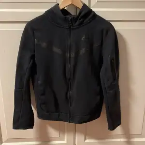 Tja! Säljer en svart nike tech hoodie köpt på nike butiken. Storlek: 147-158 L i ungdomsstorlek. Köpt för 1099kr mitt pris är 350kr. Skick: 8/10 den är använd ett fåtal gånger inga defekter eller nått på tröjan. Kom pm för flera bilder eller frågor😊