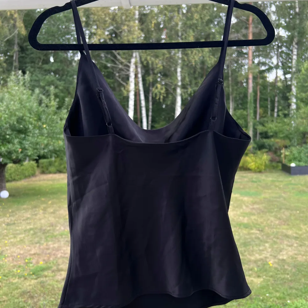 Ett svart linne i satin från Gina Tricot. Linnet är i storlek 36 men passar bra till 34 också 🤍 Endast använt en gång 🌷 Justerbara axelband.  Längd: 44 cm. Toppar.