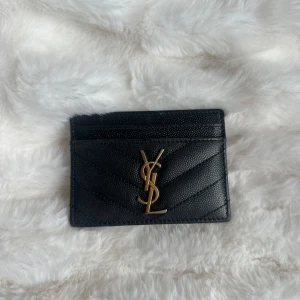 YSL korthållare - Korthållare från Saint Laurent. Äkta, kommer med dustbag, äkthetsbevis, kartong. Köpt för något år sedan. Lite slitage på kanterna & YSL  loggan, men inget som är synligt. Kolla bilderna. 