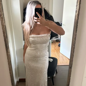 Glittrig klänning - Glittrig guldaktig balklänning/ klänning, helt ny med pris lapp kvar. Köptes för 2600 och säljs för 1200. Storlek S/M mycket bekväm och stretchig. Klänningen är från Hello Molly