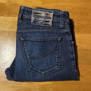 Jacob Cohen jeans - Riktigt schyssta Jacob Cohen jeans med en skön mörkblå tvätt och unika cohen detaljer som ”J” över myntfickan. Size 32. Skick 8/10 då de är i bra skick bortsätt från att lappen där bak med hästskin är lite sliten, bild 2. Priset är ej hugget i sten.