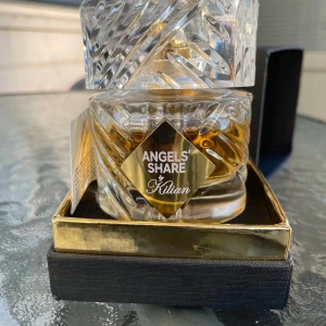 Angels' Share by Kilian Eau de Parfum - (Pris kan diskuteras) .Säljer en lyxig parfymflaska från Kilian, Angels' Share. Flaskan är i kristallklart glas med ett elegant mönster och en gyllene etikett. Den kommer i en stilren svart och guld förpackning. 