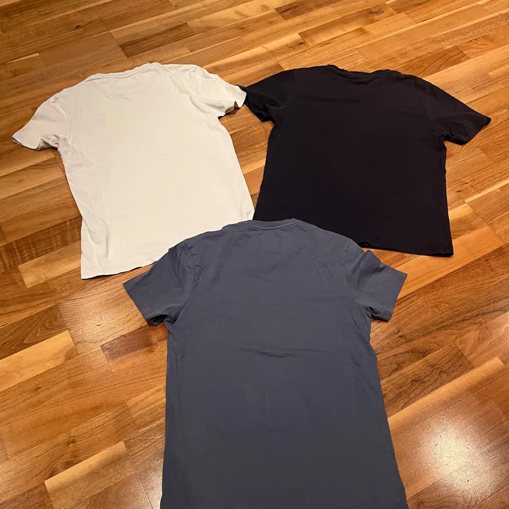 Säljer tre snygga t-shirts i olika färger. Två från Lyle & Scott i vit och blå med deras ikoniska logga, och en mörkblå från Peak Performance med tryck. Perfekta för vardagsbruk eller träning. Alla är kortärmade och i bra skick.. T-shirts.