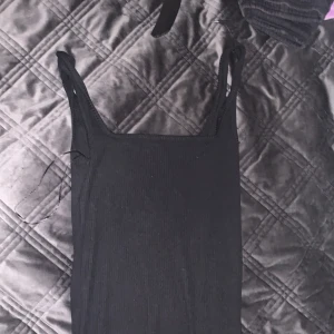 Svart ärmlös klänning från 157 - Säljer en stilren svart ärmlös klänning från 157 i storlek XS. Perfekt för både vardag och fest. Klänningen har en enkel design med smala axelband och är gjord i ett mjukt material som ger en bekväm passform. Passar utmärkt till både sneakers och klackar!