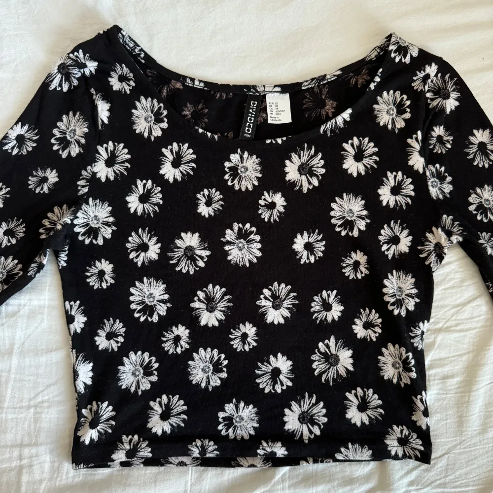 Snygg svart topp med vita blommor från H&M Divided. Den har långa ärmar och en croppad passform (crop top). Materialet är mjukt och stretchigt. Har bara använts ett fåtal gånger. Pris kan diskuteras! 🌸. Toppar.