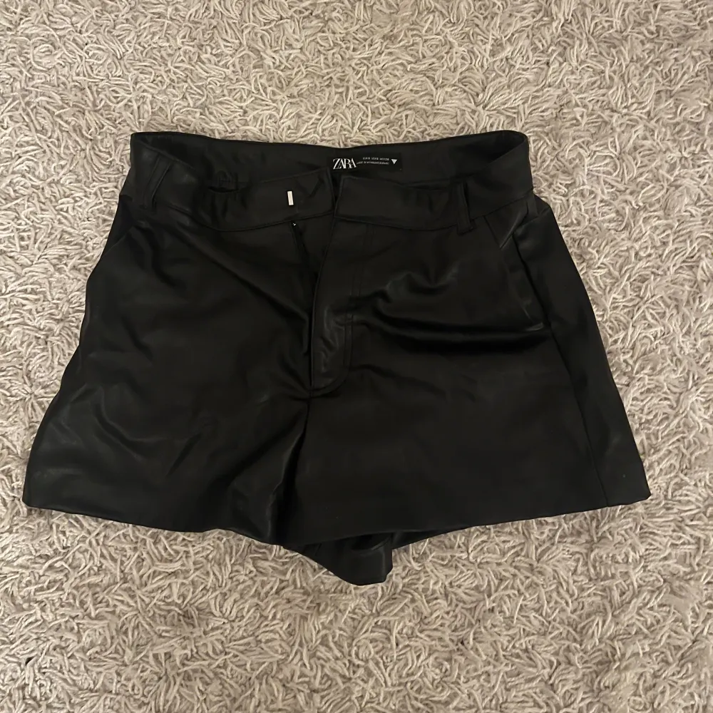 Säljer ett par snygga svarta skinnshorts från Zara. De är midwaist och har en stilren design med dragkedja fram. Perfekta för en cool look på festen eller en utekväll. Passar bra till både sommar och höst. Nästan oanvända🖤. Shorts.