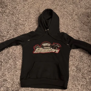 Svart hoodie och byxor från Trapstar - Säljer en svart hoodie och matchande byxor från Trapstar med coolt 'London Shooters' tryck i grått och rött. Hoodien har en klassisk passform med dragsko i huvan och byxorna har en bekväm resår i midjan. Perfekt för en avslappnad stil eller streetwear-look. Byxorna är stl m och hoodien stl s men båda passar s och m