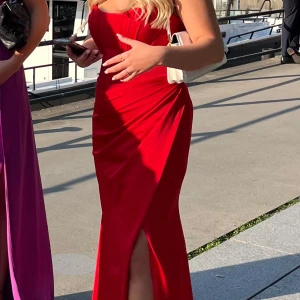 Röd långklänning - Vill nu sälja min balklänning som endast är använd en gång och tyvärr inte kommer till någon användning. Fint skick annars och har en liten slits framtil. Fler bilder kan skickas!