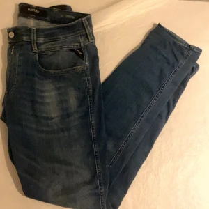 Replay hyperflex anbass  - Snygga blå jeans från Replay med en klassisk femficksdesign. De har en dragkedja och knapp framtill samt en diskret logga på bakfickan. Perfekta för en avslappnad stil. Liten slitning vid höger knä annars perfekt skick, säljer för ja inte använder de längre 
