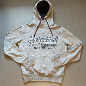SuperDry Hoodie - Säljer en jävligt fet SuperDry hoodie med stor logga på bröstet. Helt ny skick. Modellen är från 2000-2010 talet. Sitter riktigt skönt och nice passform. Priset kan diskuteras med rätt bud