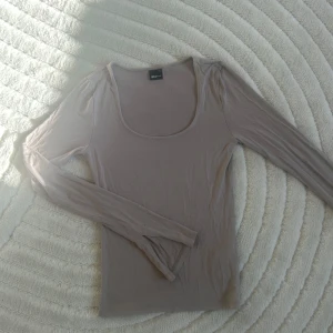 Beige/rosa långärmad topp från Gina Tricot - Säljer långärmad topp från Gina Tricot. Perfekt för lager-på-lager eller att bära som den är. Toppen har en rund halsringning med slits längst ner på armen🩷passar även XS