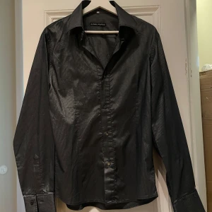 Figursydd skjorta - Figursydd skjorta i mörkgrå/silver färg. Fint skick förutom översta knappen som saknas.