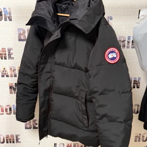 Canada Goose  - Säljer en Canada Goose med en klassisk design. Jackan har en hög krage och dragkedja framtill, perfekt för kalla dagar. Den är långärmad och har en huva för extra skydd mot väder och vind. Mycket bra kvalité, den är helt ny. Priset kan diskuteras vid snabb och smidig affär
