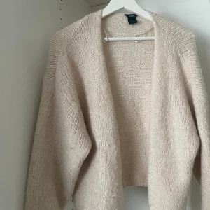 Beige stickad kofta från Lindex - Mysig beige stickad kofta från Lindex. Perfekt för kyliga dagar med sin mjuka och bekväma passform. Koftan har långa ärmar och en öppen design som gör den lätt att matcha med olika outfits.