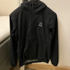 Svart windbreaker från Haglöfs. - Snygg jacka, snappt använd. Passar 190 cm.