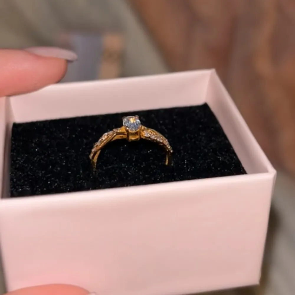 PRIS KAN DISSKUTERAS! Elegant 21K guld ring med en stor glittrig sten i mitten och mindre stenar längs sidorna. Kommer i en snygg presentask!❤️. Asusteet.