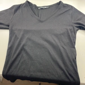 Svart ribbad tröja från 157 - Säljer en stilren svart ribbad tröja från 157 i storlek S passar även xs. Tröjan har en v-ringad hals och långa ärmar, perfekt för en enkel och bekväm look. Passar bra till både jeans och kjol. Hör av dig vid intresse!