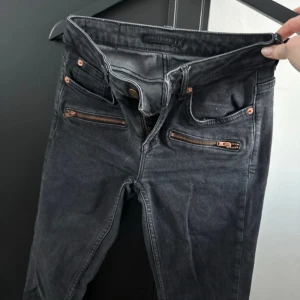 Svarta jeans från Perfect Jeans - Snygga svarta jeans från Perfect Jeans med dragkedjedetaljer på fickorna. De har en tight passform och är perfekta för en stilren look. Klassisk femficksdesign och knappgylf.