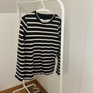 Randig långärmad tröja från levate - Säljer en stilren randig långärmad tröja från levate i svart och vit. Perfekt för en avslappnad look. Tröjan har en klassisk rund halsringning och är tillverkad i ett mjukt material.