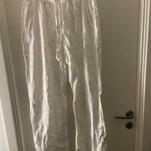 Vita linnebyxor från 157 - Snygga vita linnebyxor från 157 med elastisk midja och snörning. Perfekta för en avslappnad stil. Byxorna har en lös passform och är tillverkade i ett lätt och luftigt material.