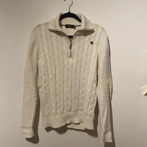 Vit stickad tröja från Morris 1/4 zip - Säljer en stilren vit stickad tröja från Morris med kabelstickat mönster och dragkedja vid halsen. Tröjan har långa ärmar och ribbade muddar vid ärmslut och nederkant. Perfekt för kyliga dagar!