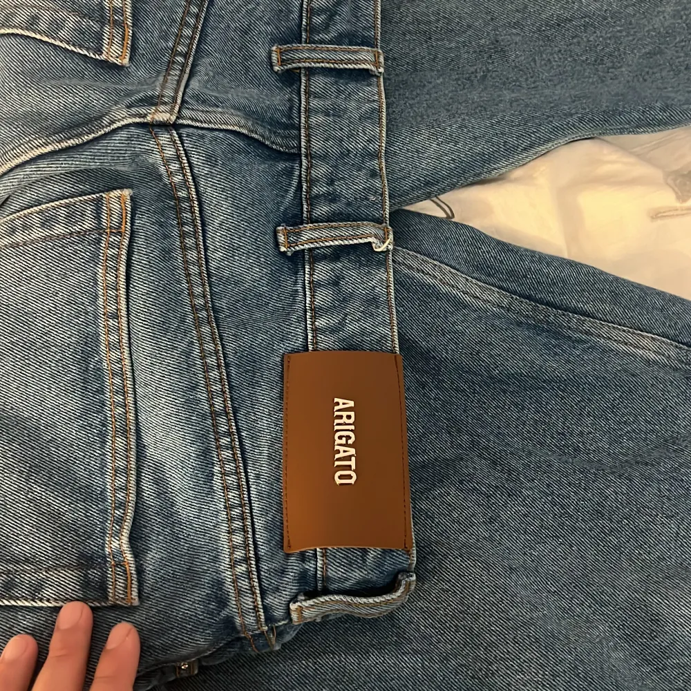 Snygga blå jeans från Axel Arigato med klassisk femficksdesign och en bekväm passform. De har en dragkedja och knapp framtill samt en stilren läderpatch med logotyp baktill. Perfekta för en avslappnad stil.. Farkut & Housut.