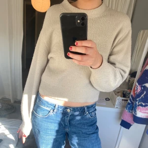 Beige stickad tröja från & Other Stories - Säljer en stilren beige stickad tröja från & Other Stories. Tröjan är croppad med långa ärmar och har en rund halsringning. Lite knopprig men annars fint skick. 