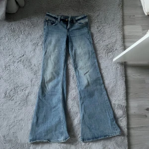 Blå low flare jeans - Snygga blå flare jeans med mycket låg midja. De har en klassisk femficksdesign och en knappgylf. Fin ljusblå färg, väldigt sköna och endast använda ett fåtal gånger!!