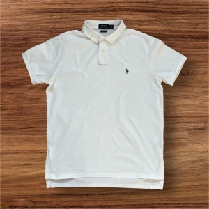 Vit pikétröja från Ralph Lauren - Säljer en klassisk vit pikétröja från Ralph Lauren med den ikoniska broderade logotypen på bröstet. Tröjan har korta ärmar och en stilren krage med knappar. Perfekt för en finare middag och till en härlig sommardag. Mitt pris är endast 199kr men man får 10% rabatt om man blir en följare! Ställ gärna frågor!