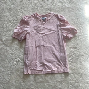 Rosa t-shirt från Aware - Söt rosa t-shirt från Aware med puffiga kortärmar och rund halsringning. Perfekt för en avslappnad stil. Tillverkad i mjukt material för extra komfort.