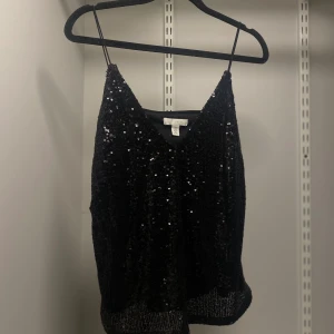 Svart paljettlinne - Snyggt svart linne med paljetter som ger en glittrig look. Perfekt för en utekväll eller fest. Axelbandslös design med en elegant passform. Från hm, storlek xs.