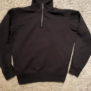Svart Halfzip - Skick 9/10. Storlek S. Snygg svart halfzip tröja och hög krage. Perfekt för en stilren look. Tröjan har långa ärmar och är tillverkad i ett mjukt bomulls material för extra komfort. Hör av er vid fler funderingar!