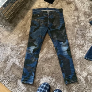 Dsquared2 jeans - Snygga jeansbyxor med ett coolt camouflage-mönster i blått och grönt. Byxorna har en klassisk femficksdesign och en knappgylf. Perfekta för en avslappnad stil med en twist. Lite Chris Heyn vibbar