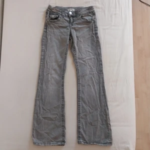 Grå jeansbyxor från Ginatricot - Snygga grå jeansbyxor från Ginatricot med bootcut-stil. Byxorna har en klassisk femficksdesign och knappar i silverfärg. Perfekta för en avslappnad look.
