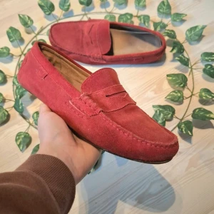 Röda mockaloafers från Ralph Lauren - Snygga röda loafers i mocka från Ralph Lauren. Skorna har en klassisk design med en stilren överdel och en robust sula med logotyp. Perfekta för en avslappnad men stilfull look.