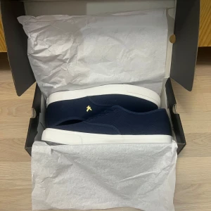 Marinblå sneakers från Lyle & Scott - Snygga marinblå sneakers från Lyle & Scott med vit sula och klassisk snörning. Skorna är helt nya i deras originals förpackning. Passar alla stilar.