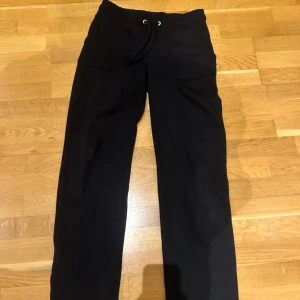 Svarta mjukisbyxor med snörning - Säljer ett par bekväma svarta mjukisbyxor med snörning i midjan. Byxorna har en loose passform och är perfekta för en avslappnad stil. De har praktiska fickor framtill.