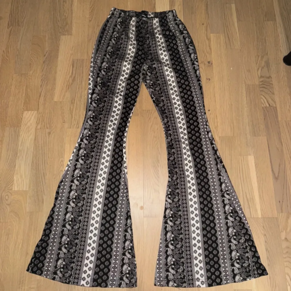 Säljer ett par snygga byxor med svart och vitt mönster. De har en skön, loose passform och är utsvängda vid benen för en retro look. Perfekta för både vardag och fest! 🖤🤍Fashionnova. Farkut & Housut.